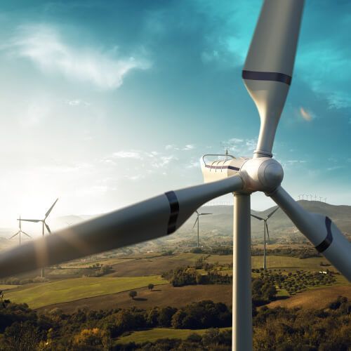 A group of wind turbines are sitting in the middle of a field.