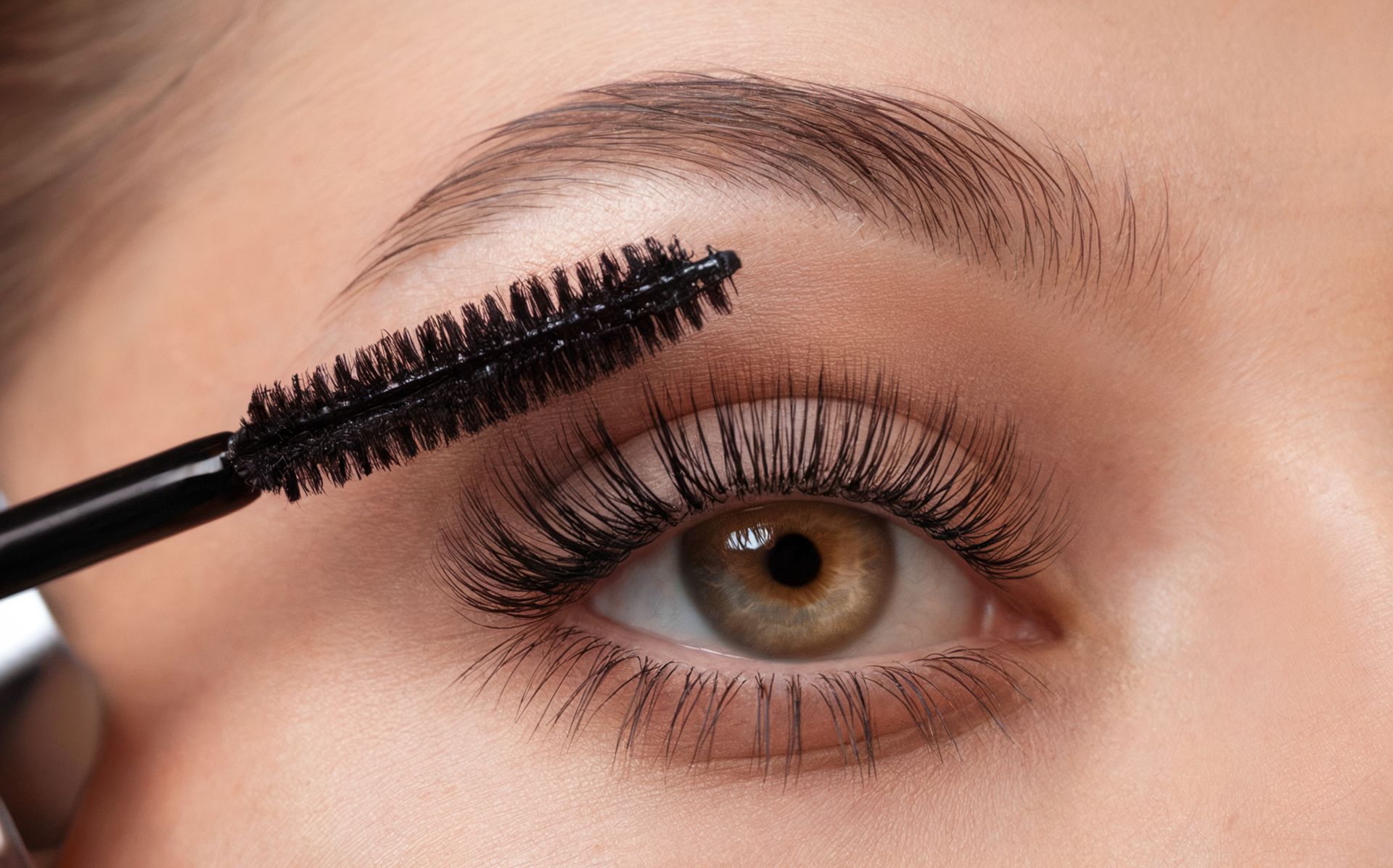 Eine Frau trägt Wimperntusche auf ihr Auge auf.