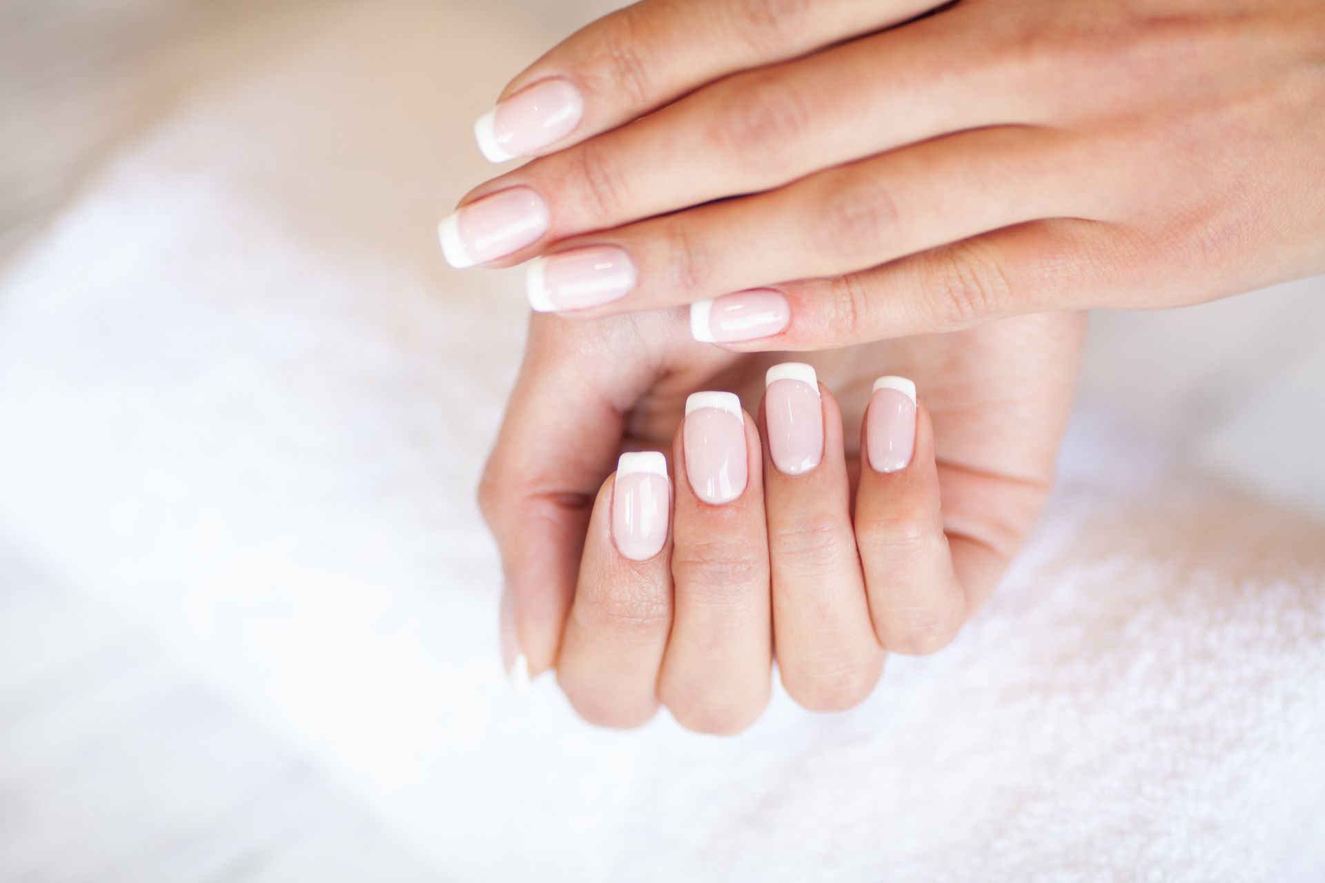 Eine Nahaufnahme der Hände einer Frau mit French Manicure.