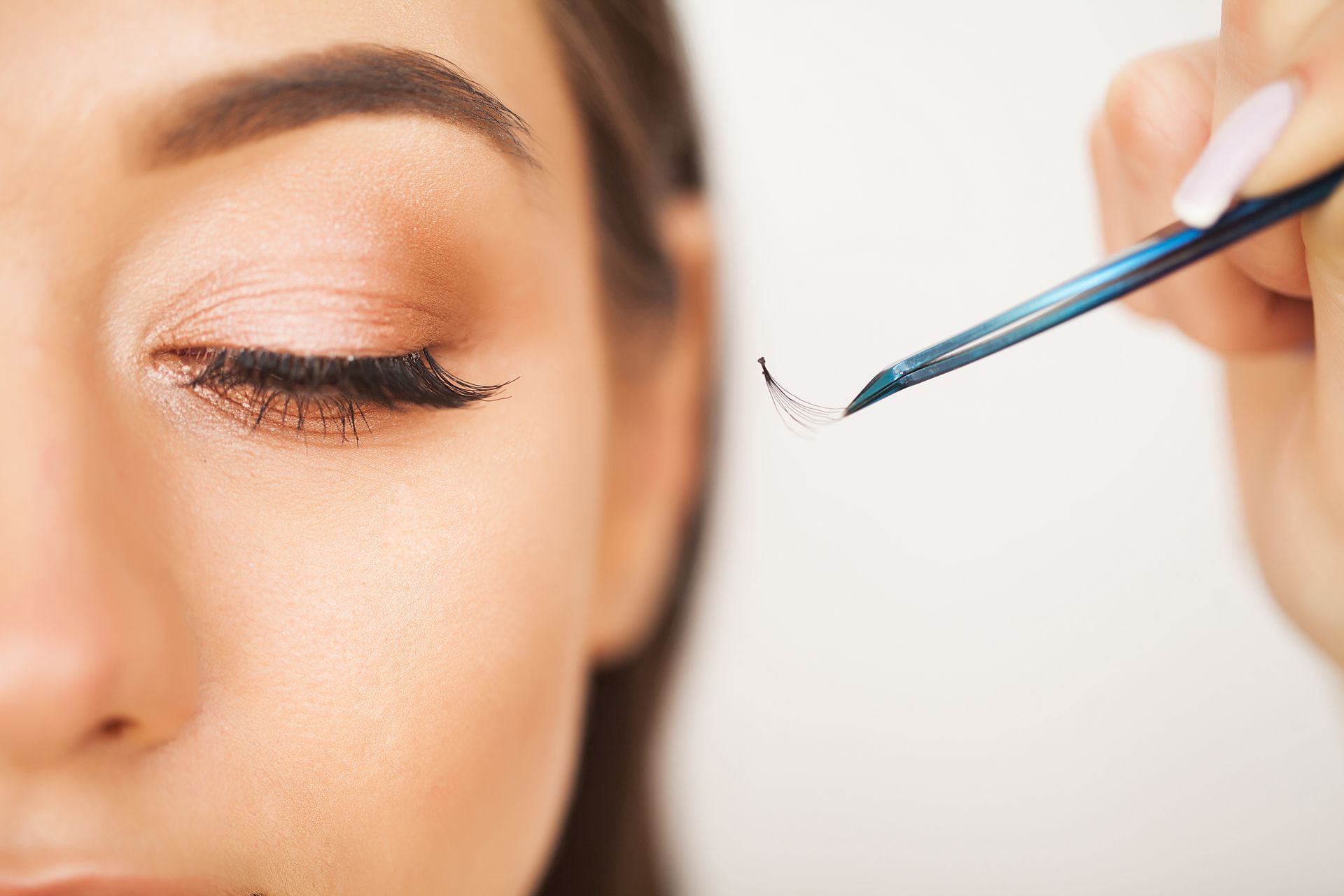 Eine Frau lässt sich von einem Visagisten die Wimpern machen.