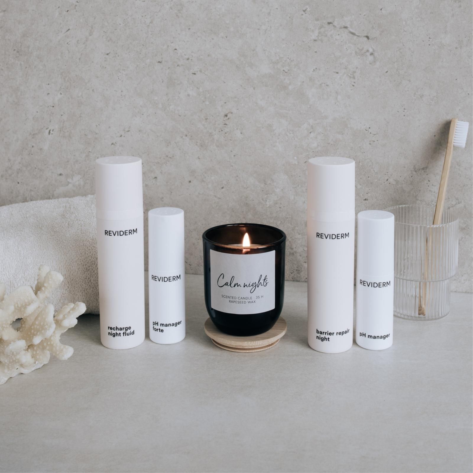 Auf einem Tisch steht eine Kerze neben einer Zahnbürste und einem Handtuch.