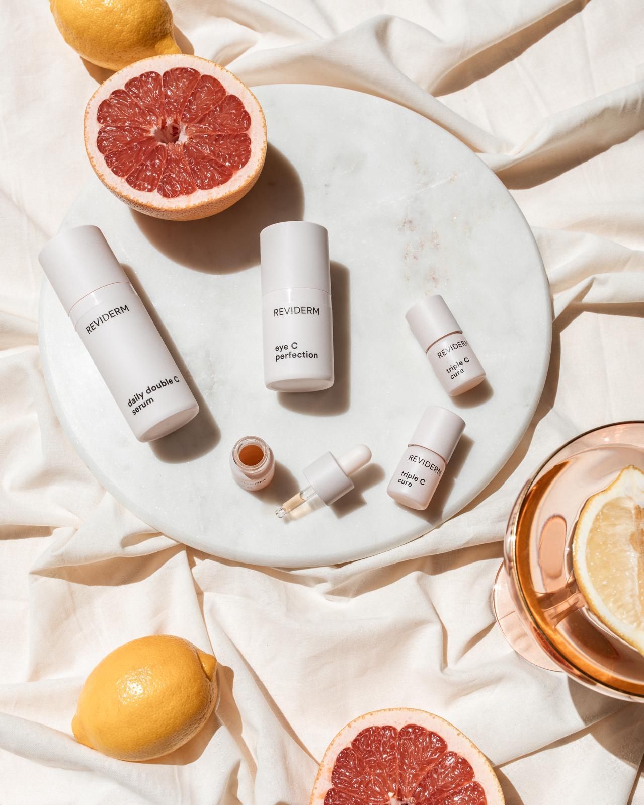 Ein weißer Teller mit Kosmetikflaschen und Grapefruitscheiben.