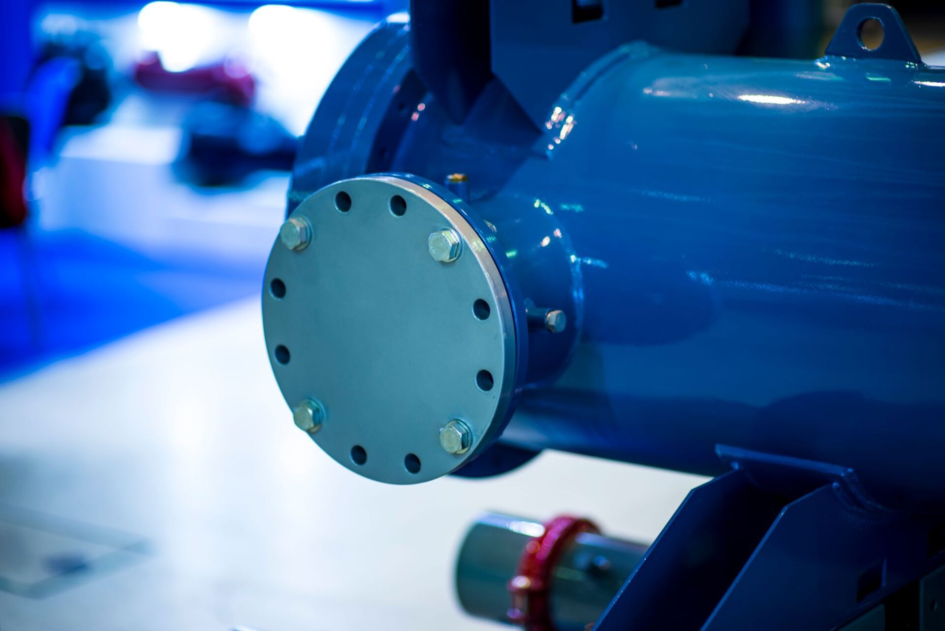 Attrezzatura industriale blu, primo piano di una flangia circolare con bulloni, installata all'interno.
