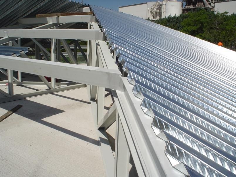 Primo piano di una struttura in acciaio bianco che sostiene nuovi pannelli riflettenti in metallo ondulato.