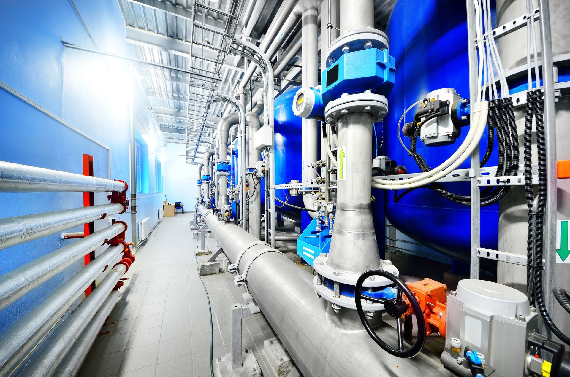 Interno industriale con serbatoi, tubi e macchinari blu.