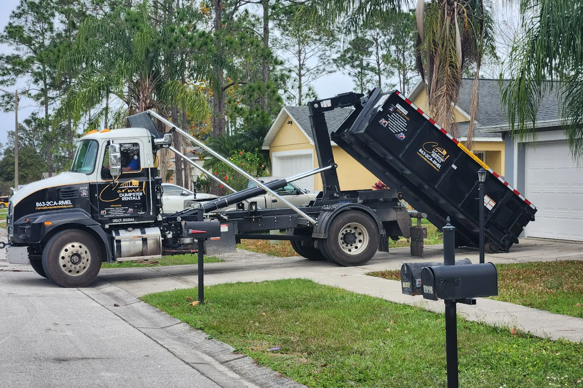 Dumpster being delivered to a residential home in Lakeland, FL by Carmel Dumpster Rentals