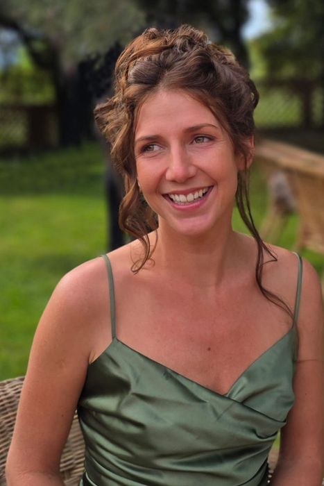 A woman with long dark hair is smiling for the camera.