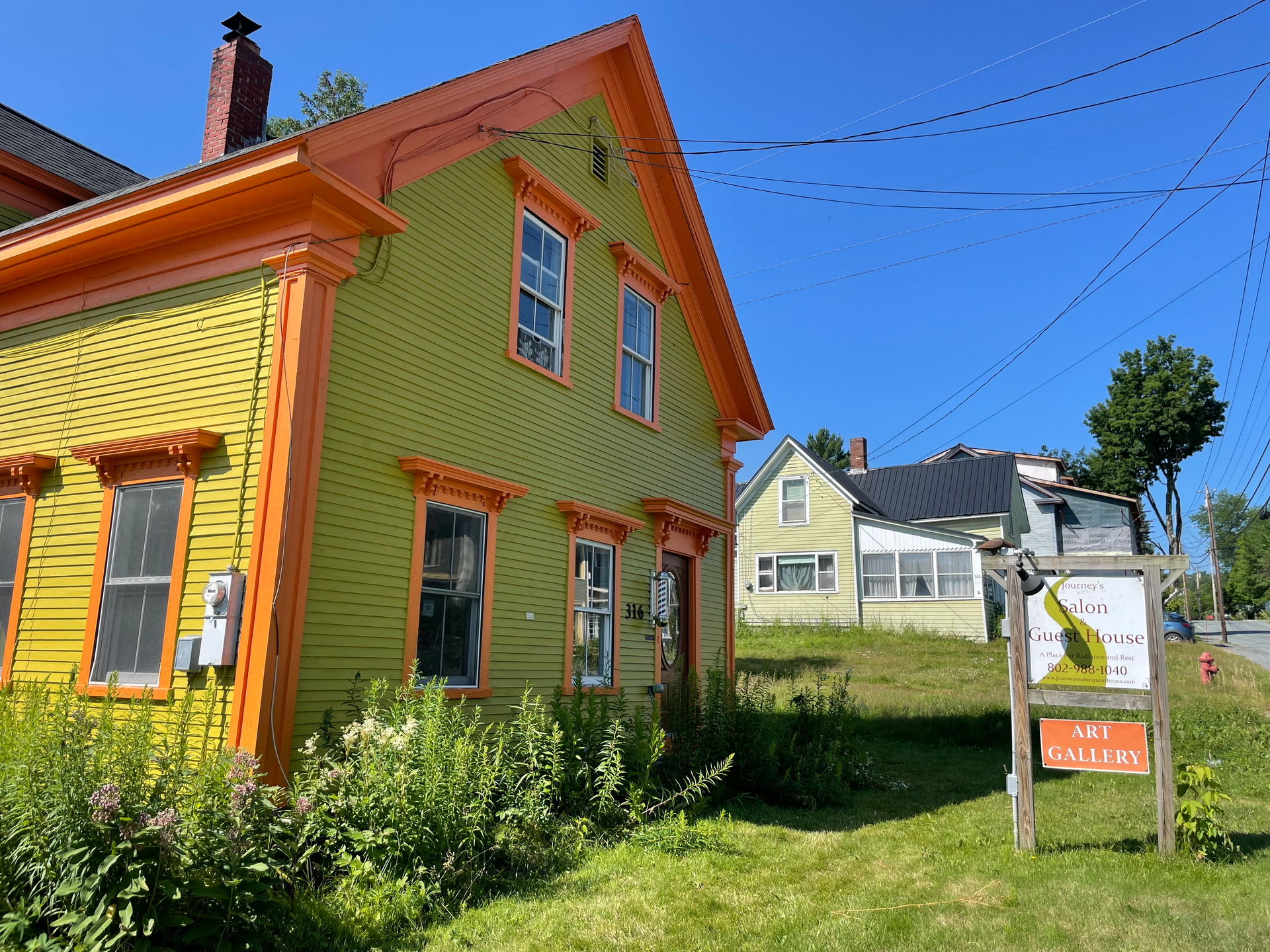 A yellow and orange house with a sign in front of it