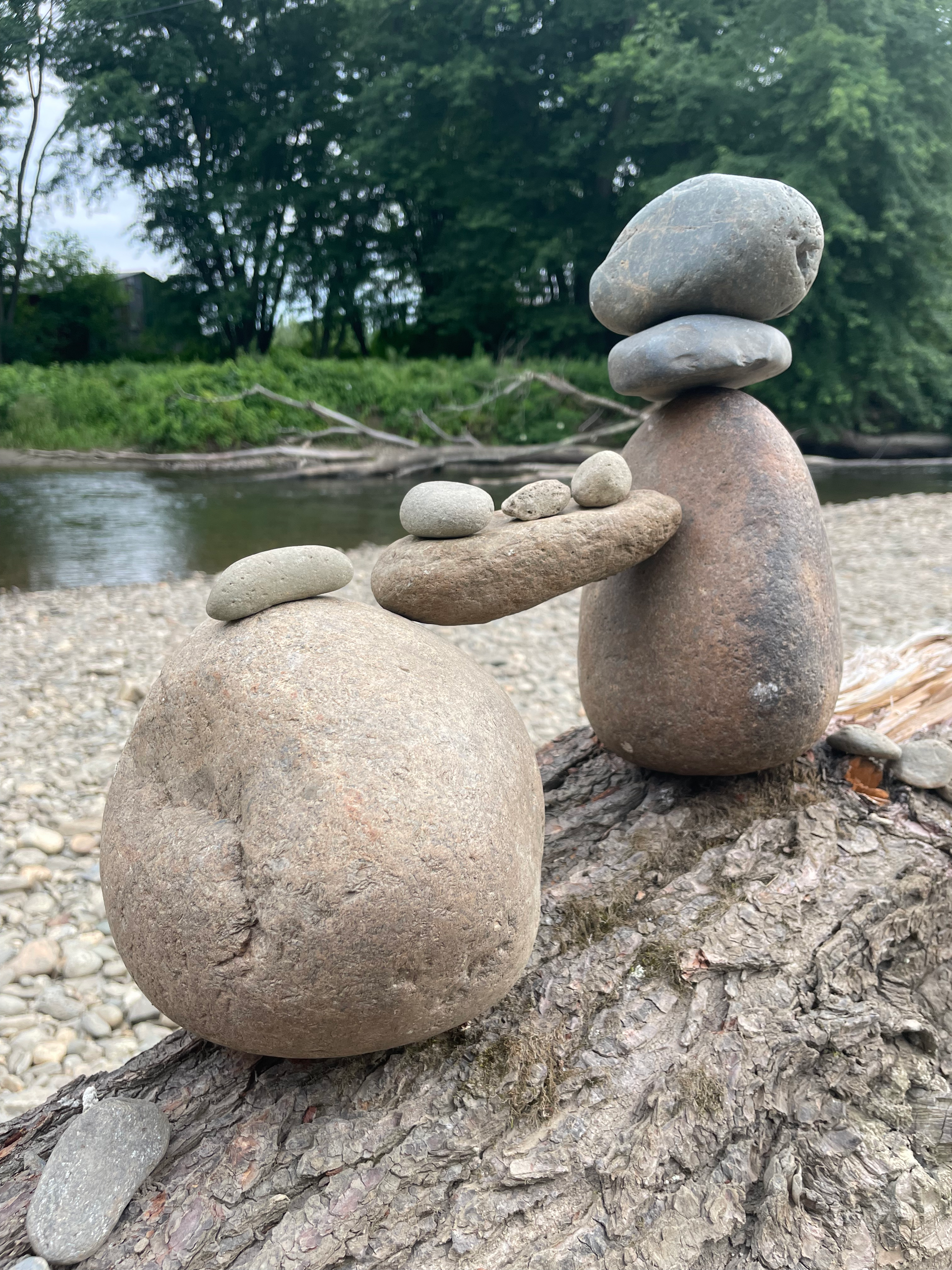 Two rocks are stacked on top of each other on a log.