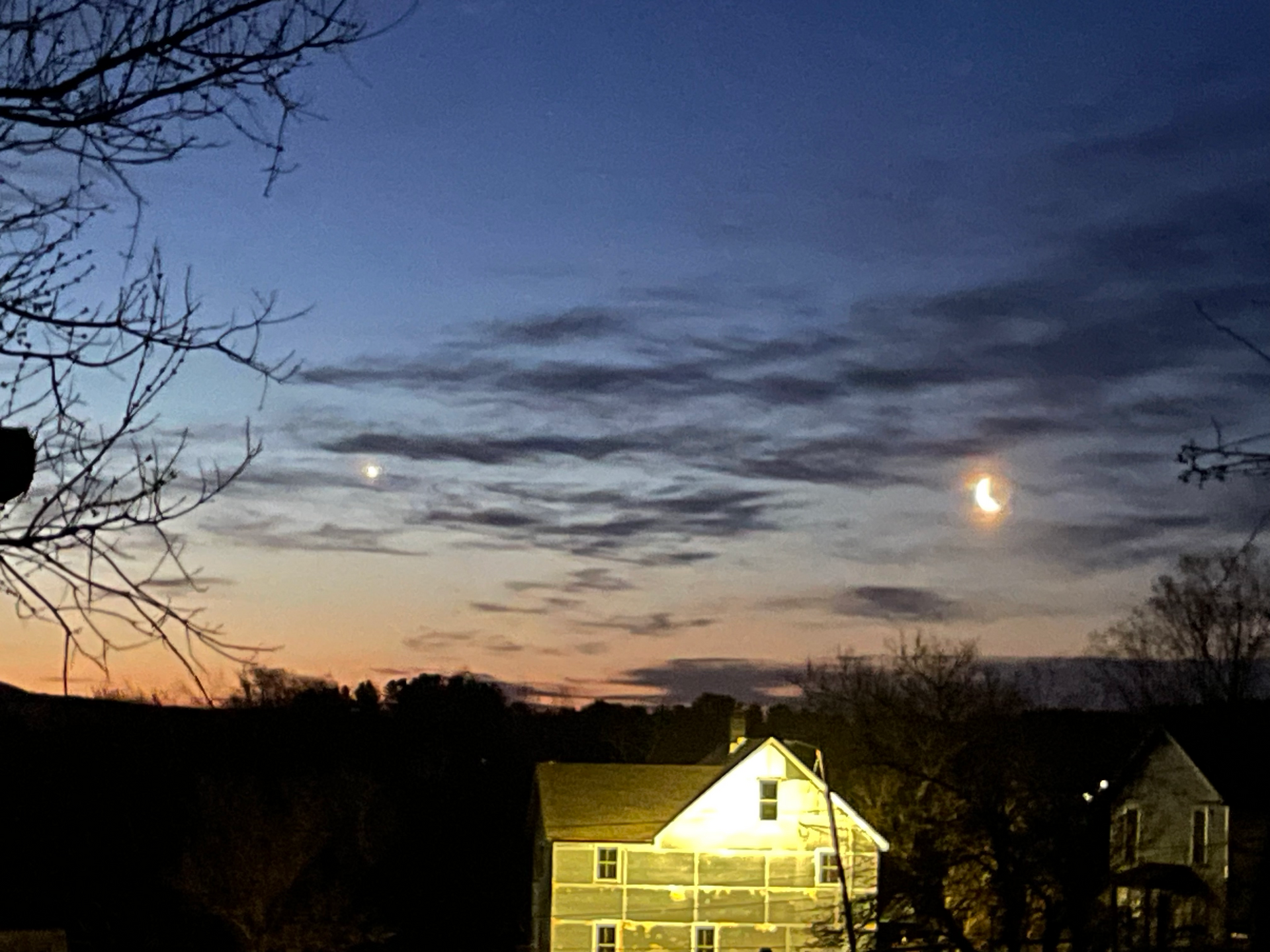 A house is lit up at night with a full moon in the sky