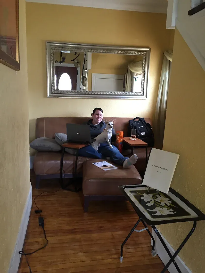 A woman is sitting on a couch with a laptop