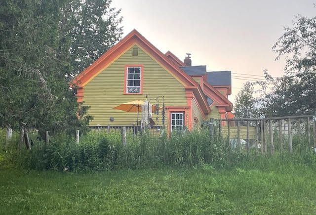 A yellow and orange house with a fence in front of it in North Troy, Vermont