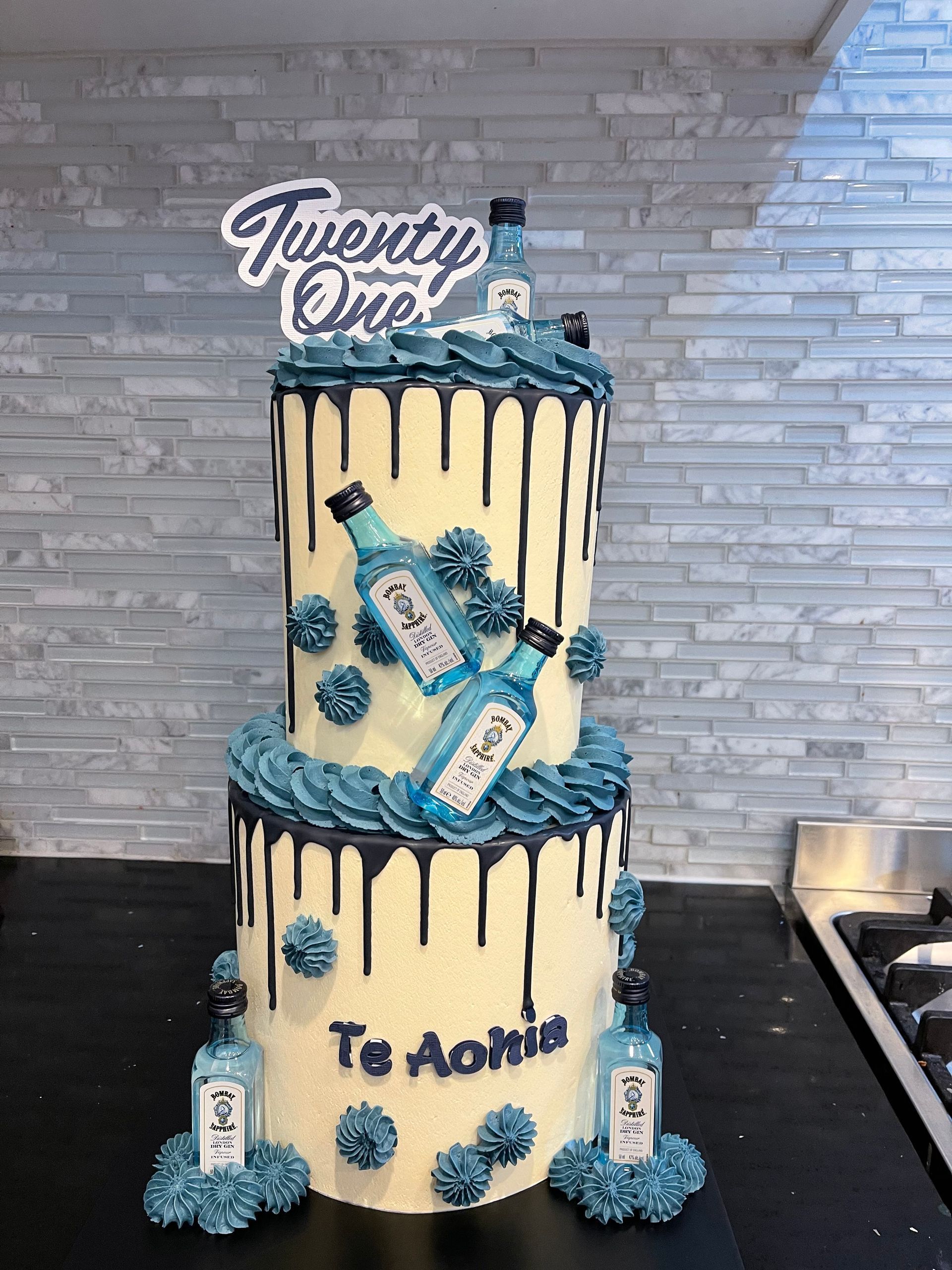 A cake with two bottles of gin on top of it is on a table.