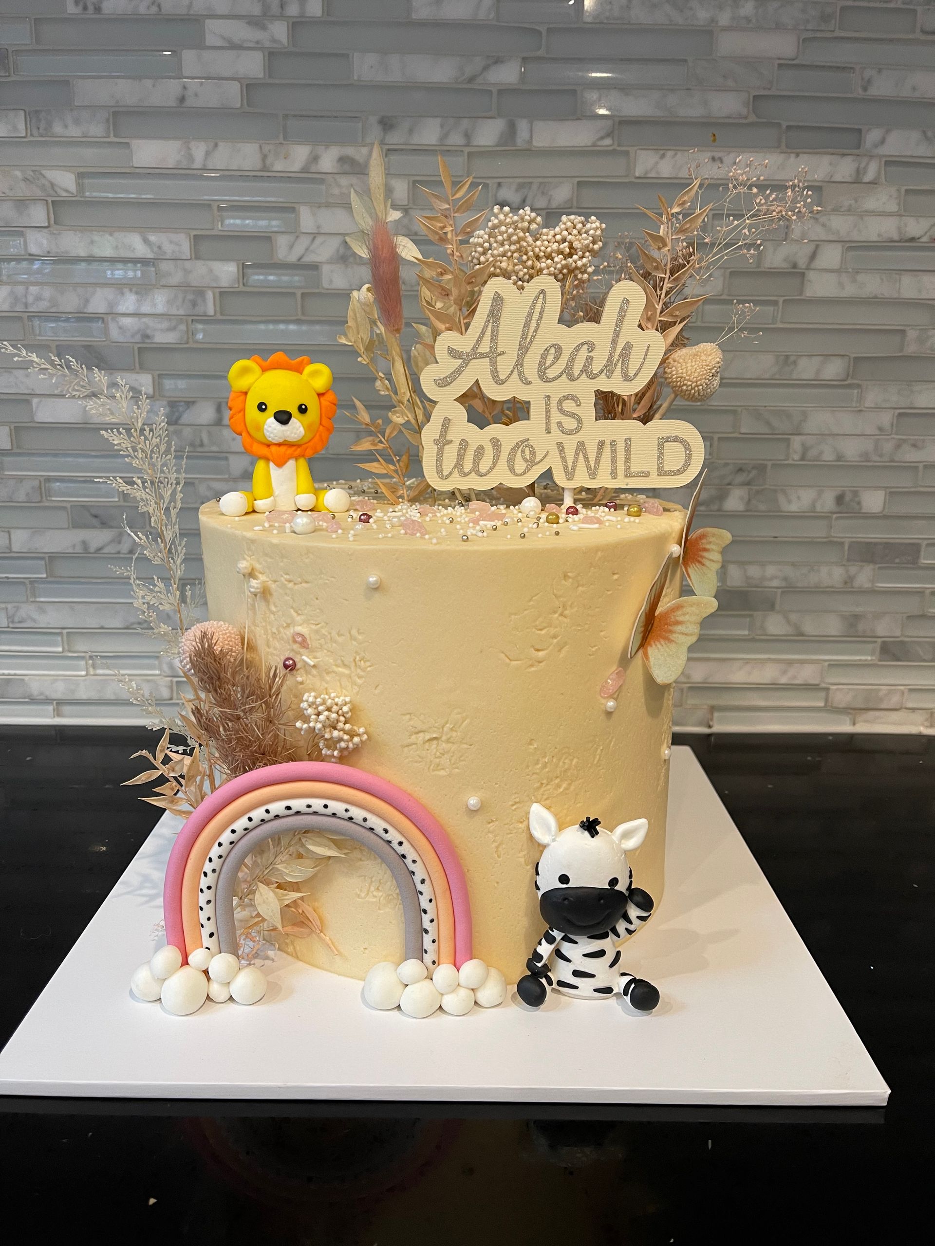A cake with a zebra and a lion on top of it is on a table.