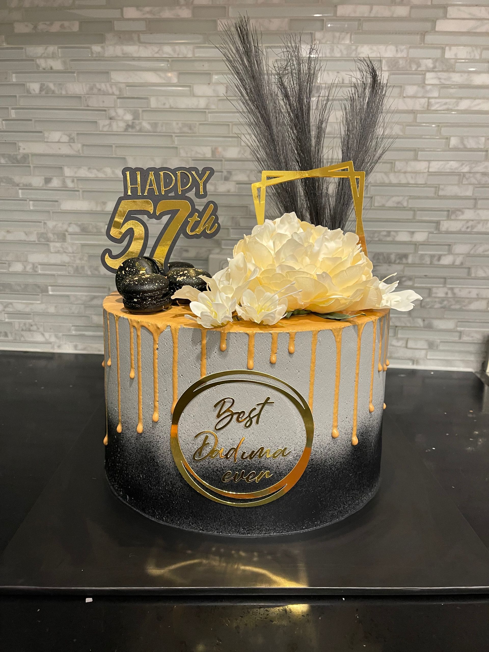 A black and gold birthday cake is sitting on a counter.