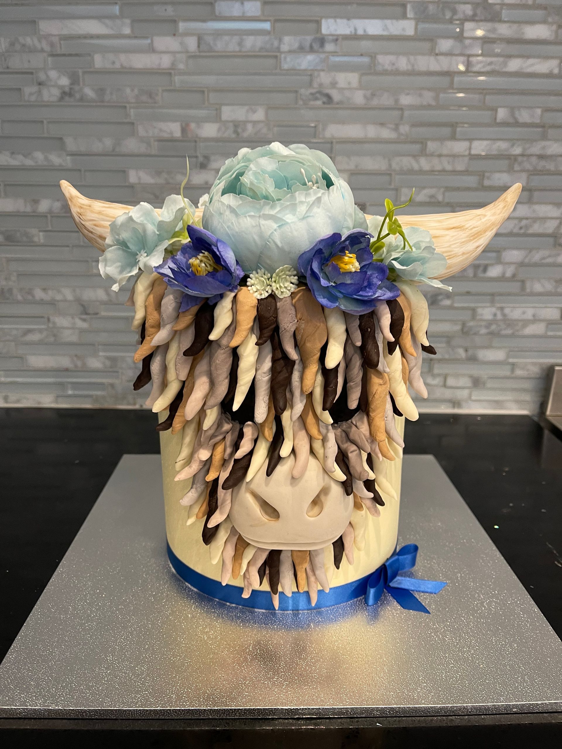 A cake in the shape of a cow with horns and flowers on it.