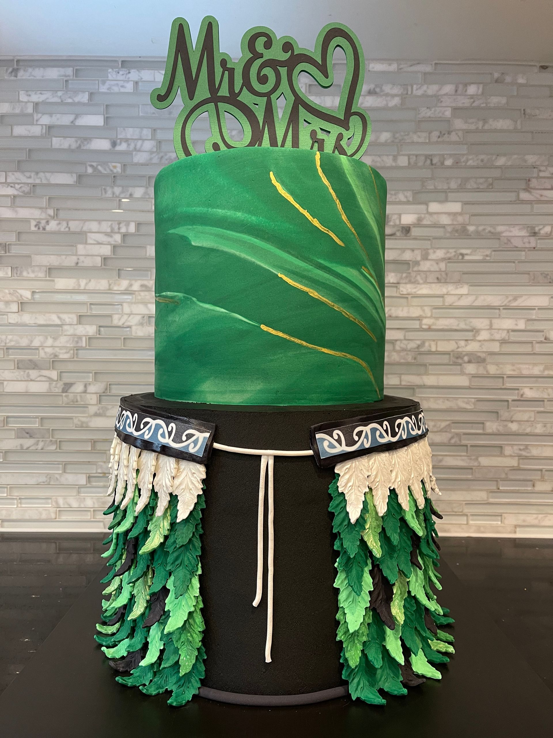 A green and black cake with a topper is sitting on a table.