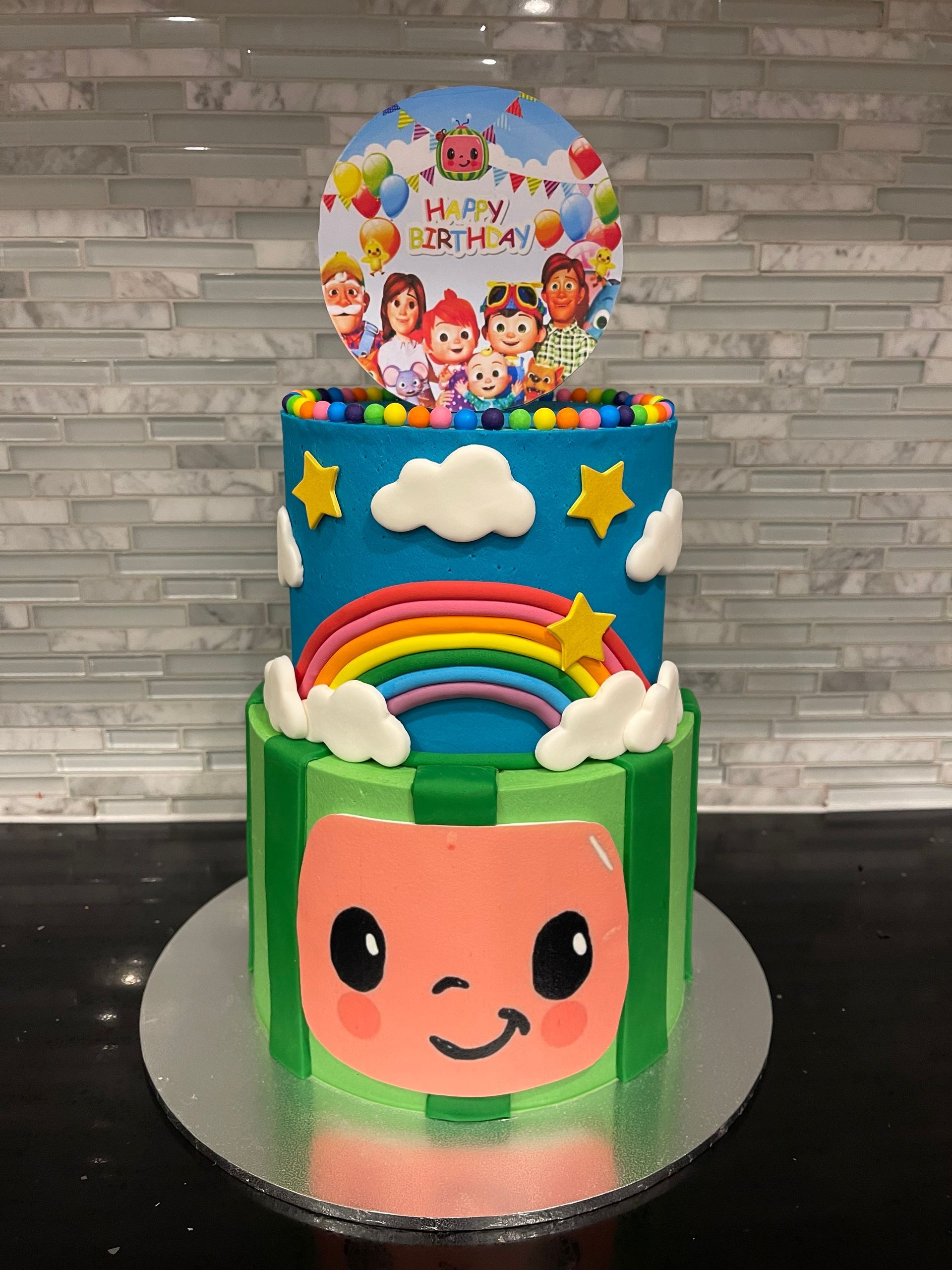 A cake with a rainbow , clouds and stars on it is on a table.