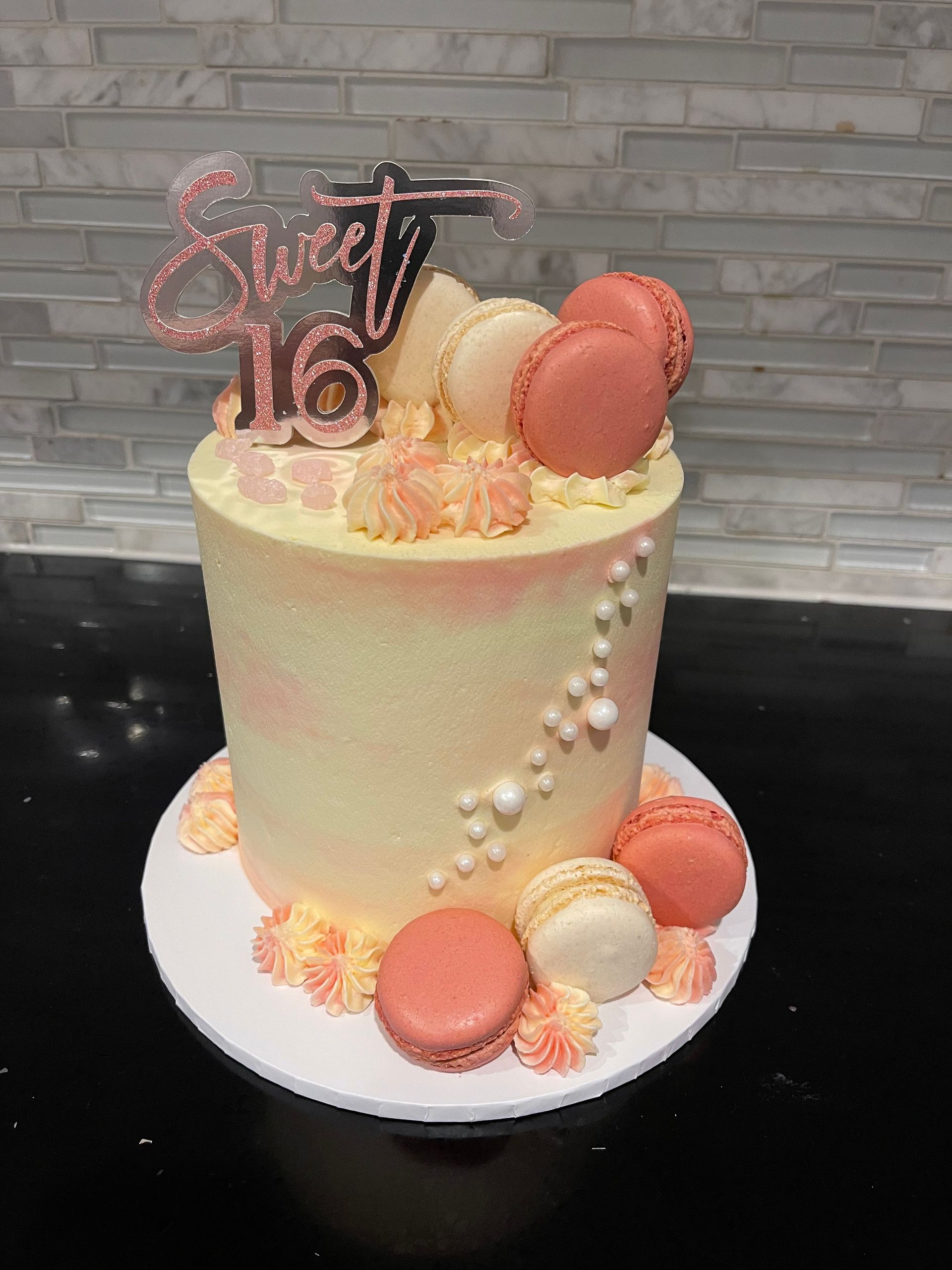 A cake with macarons and pearls on it is on a table.