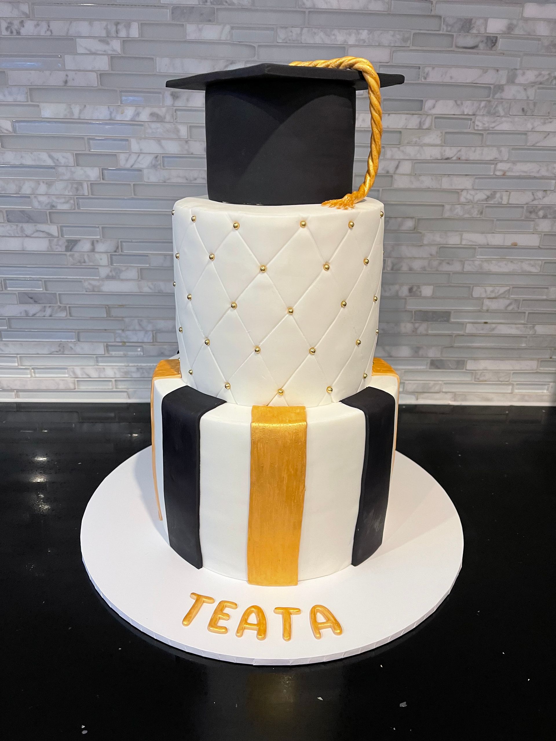 A black and white graduation cake with a graduation cap on top