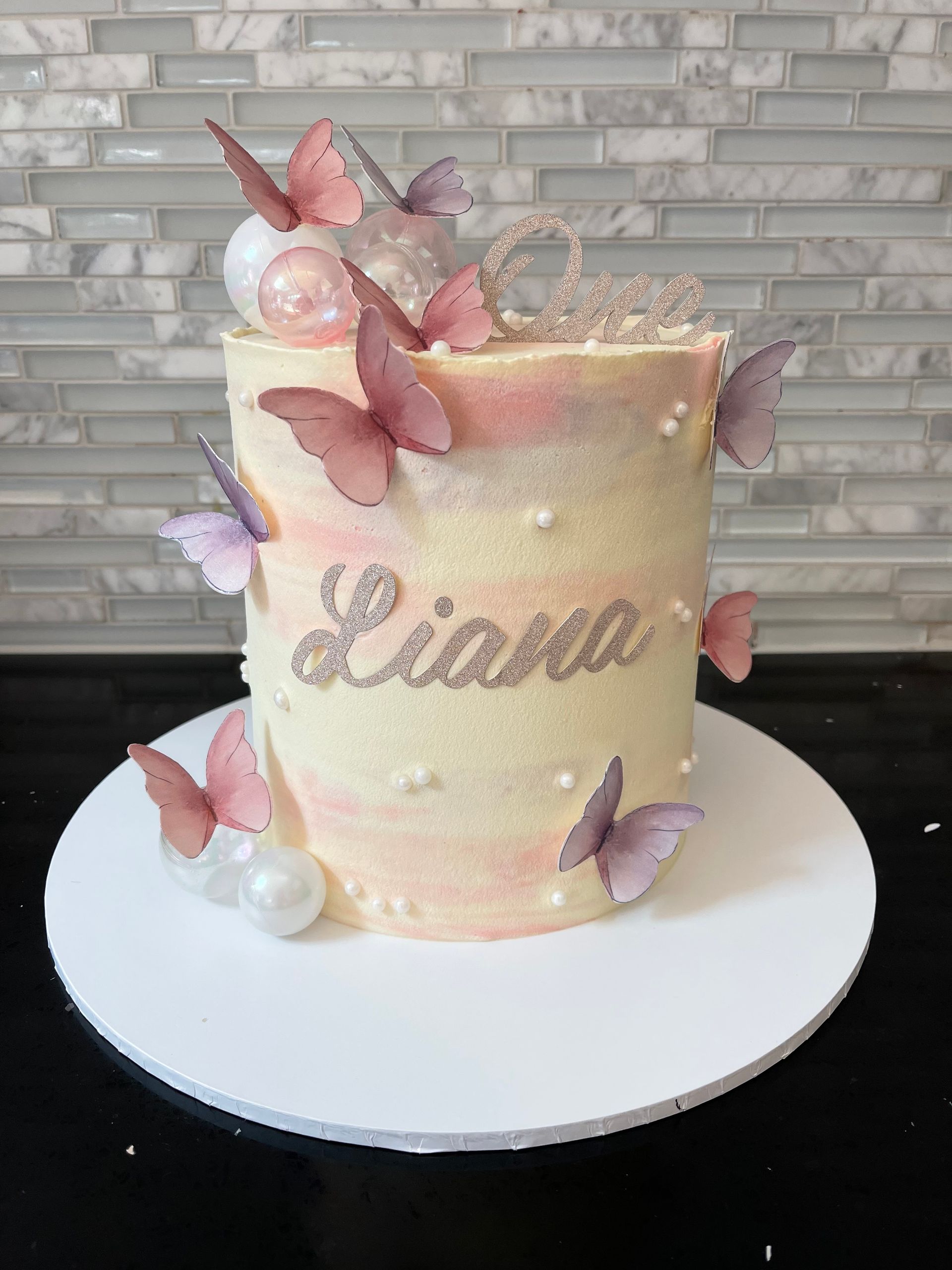 A cake with the name liana and butterflies on it