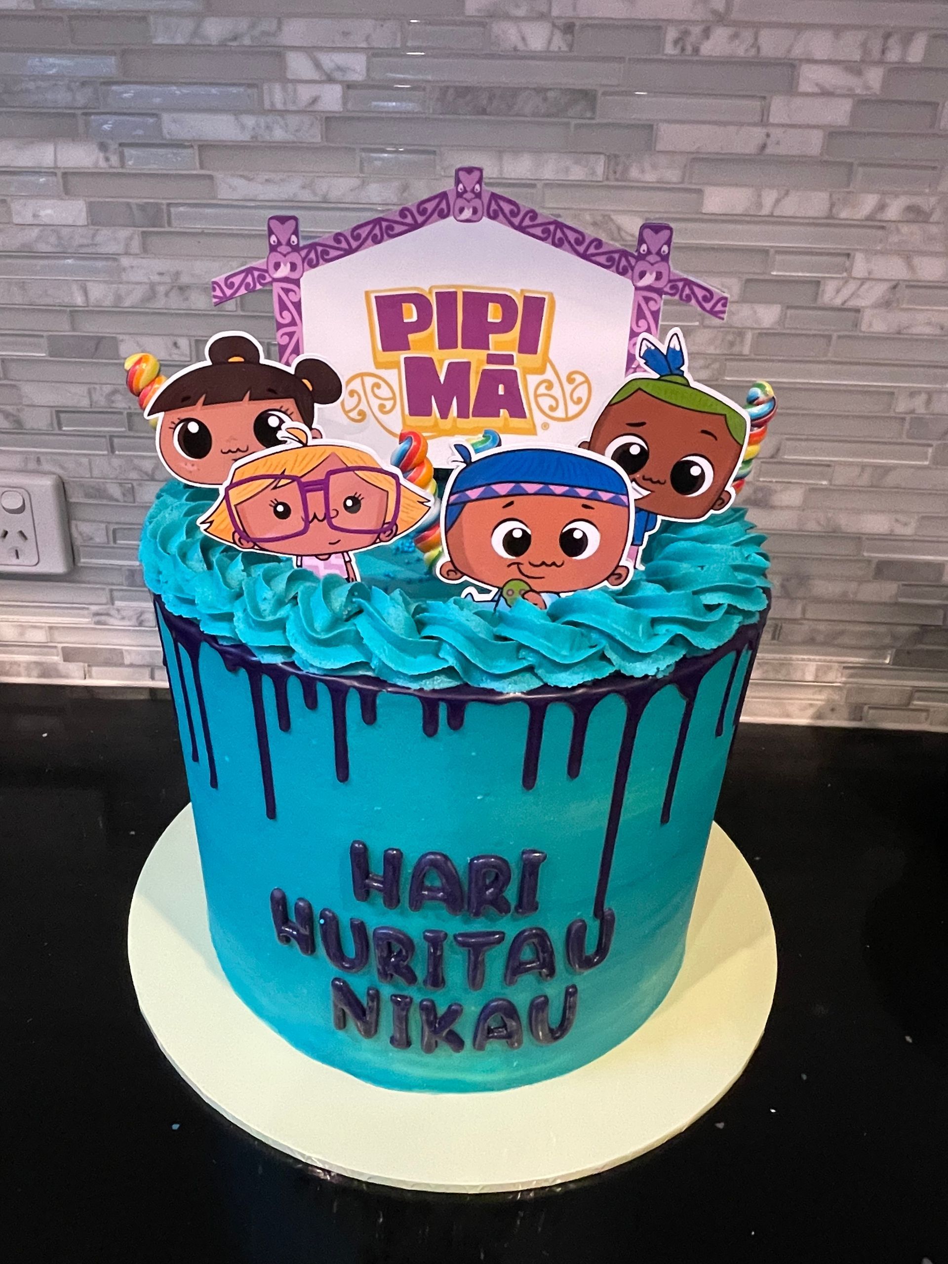 A blue cake with cartoon characters on it is on a table.