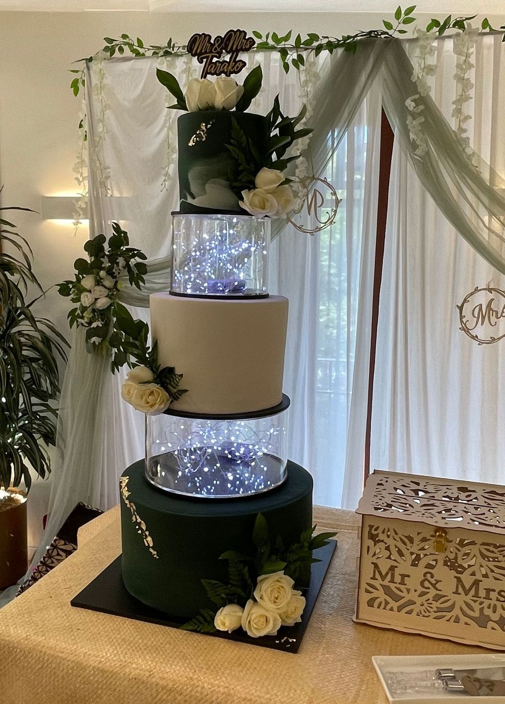A wedding cake is sitting on top of a table in a room.