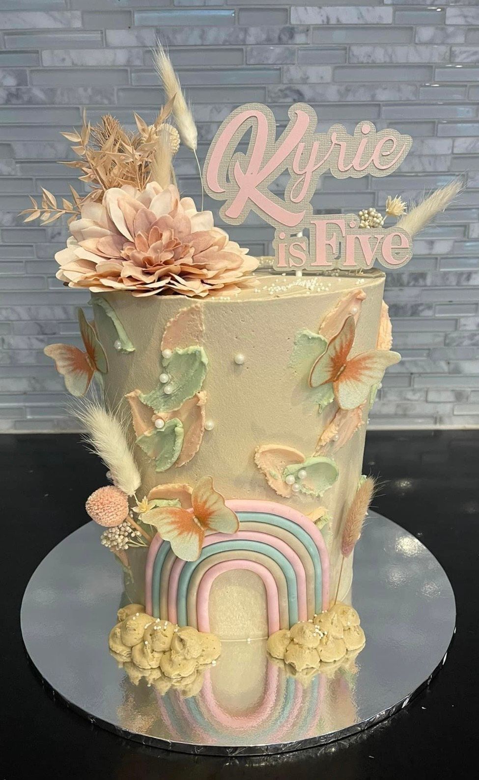 A cake with a rainbow and flowers on it is sitting on a table.
