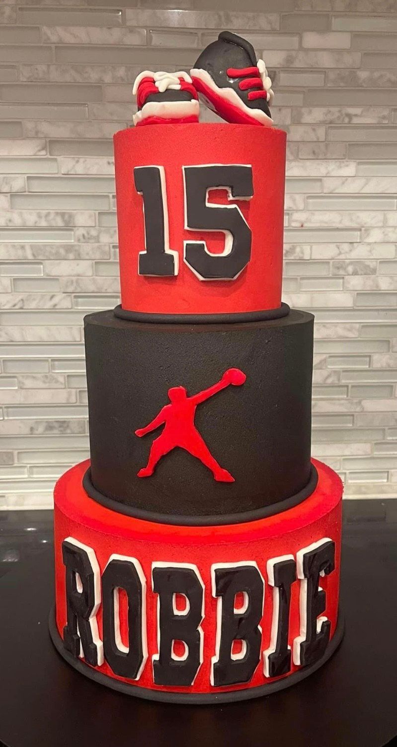A red , black and white cake with the name robbie on it.