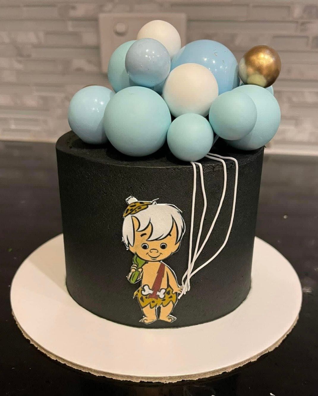 A cake with a picture of bam bam and balloons on it