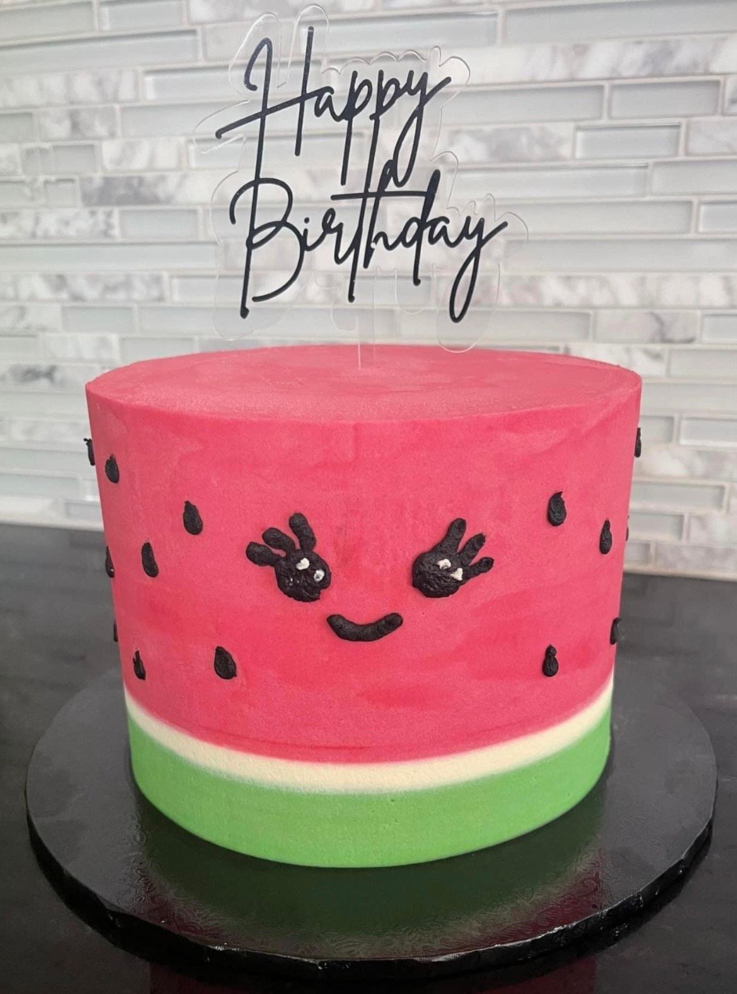 A watermelon birthday cake with a happy birthday topper on top of it.