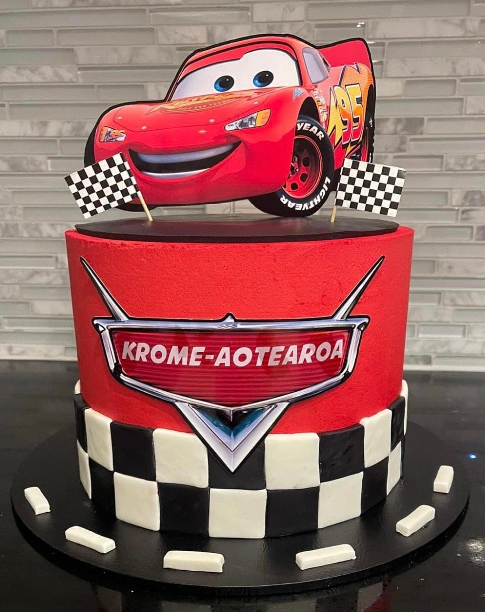 A cake with a lightning mcqueen on top of it.