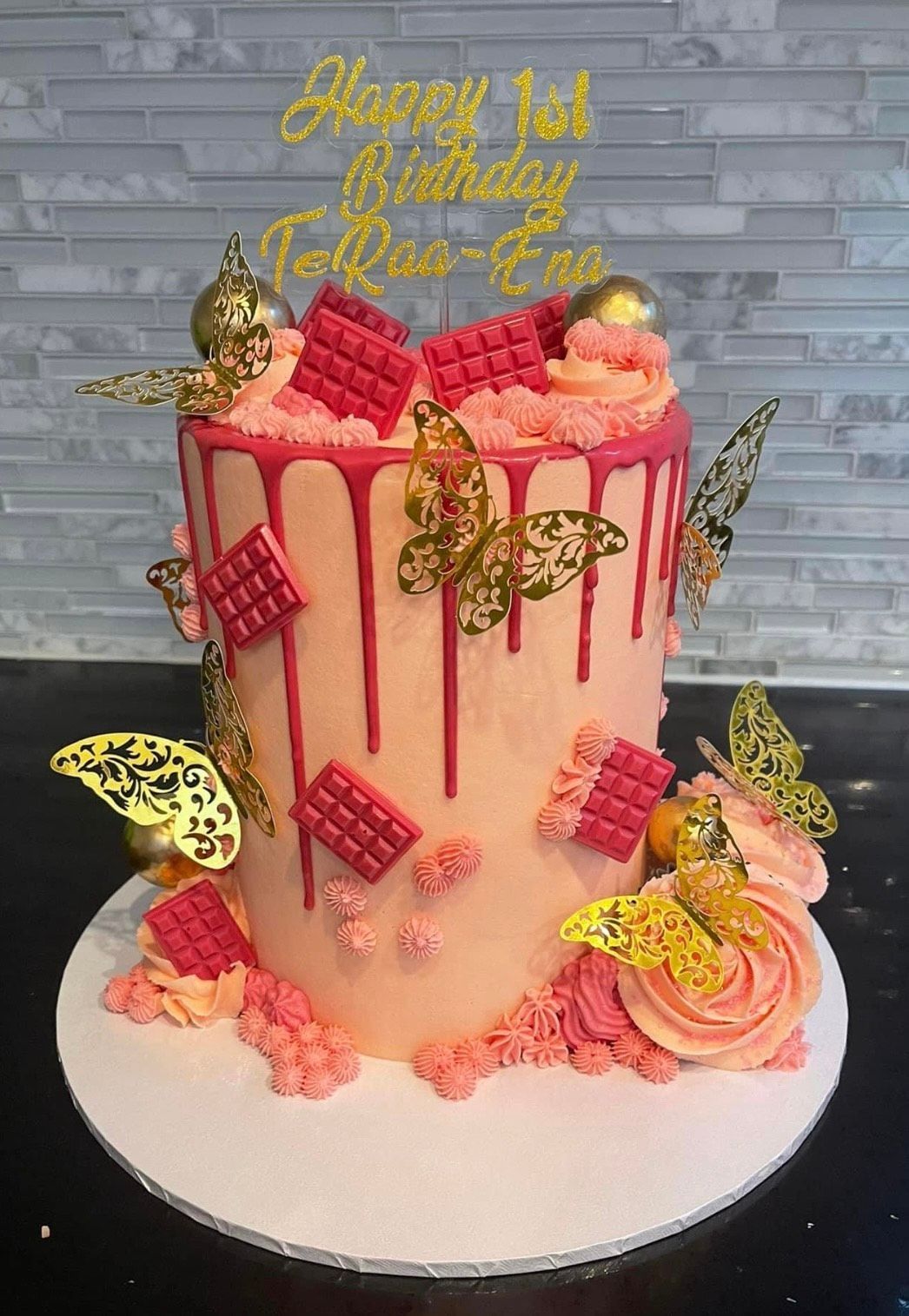 A pink cake with butterflies on it is on a table.
