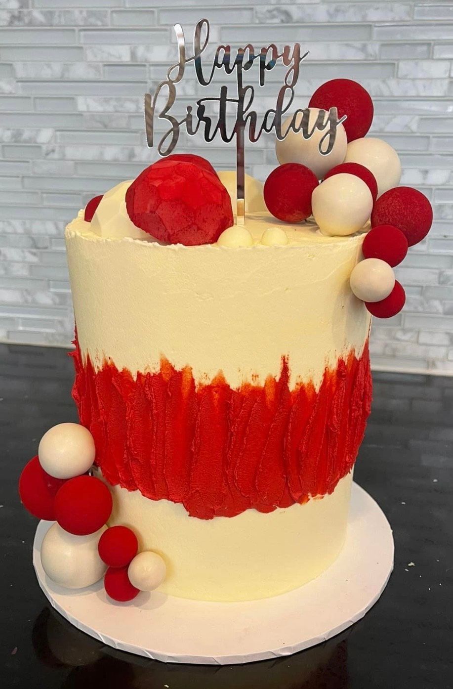 A birthday cake with red and white frosting and a happy birthday topper.