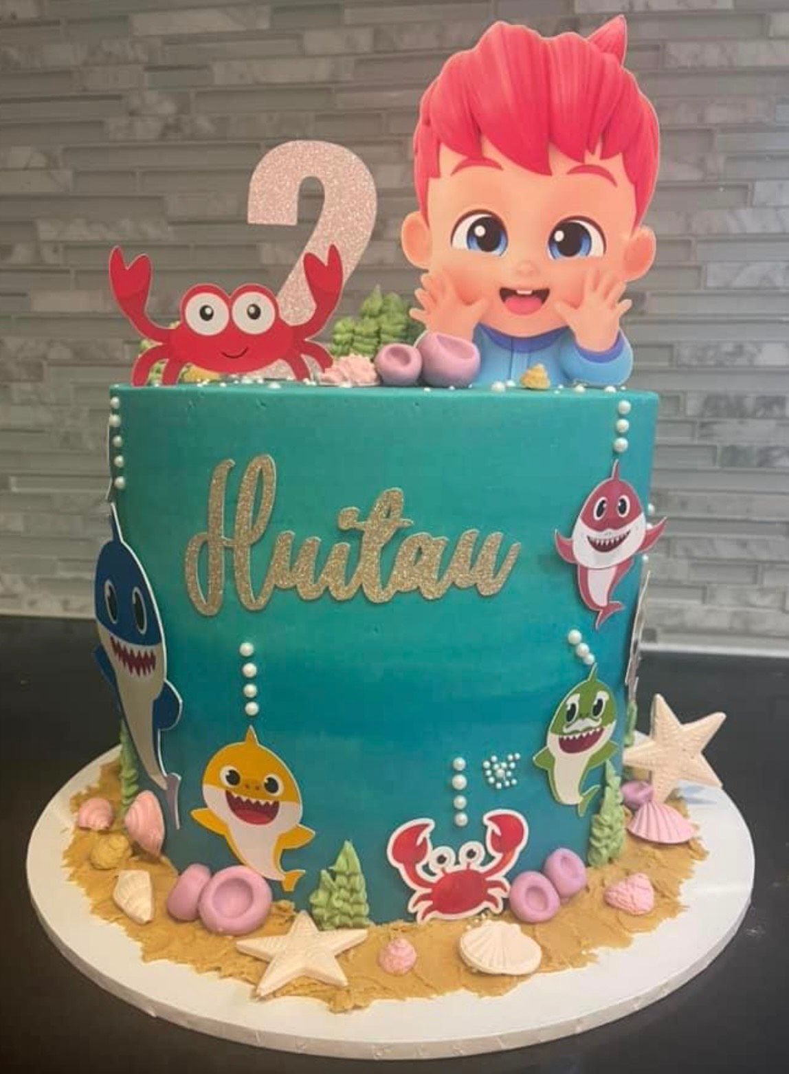 A baby shark cake with a boy on top of it.