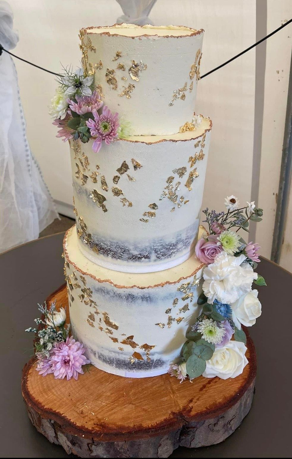 A wedding cake is sitting on top of a wooden stump.
