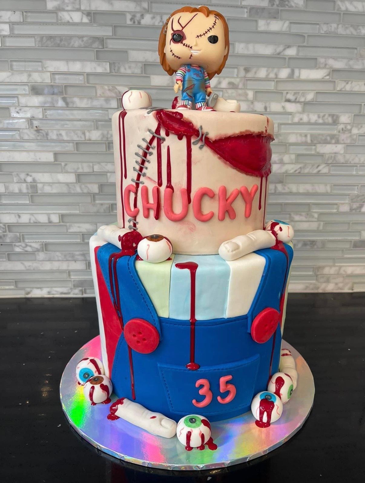 A cake with a figurine of chucky on top of it.