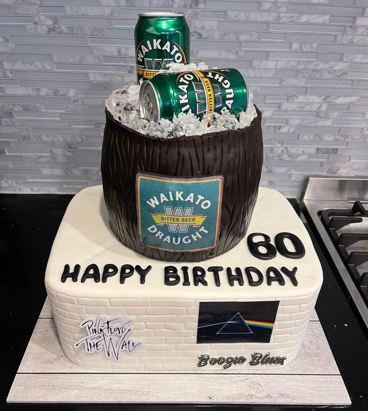 A birthday cake with three cans of beer in a barrel.