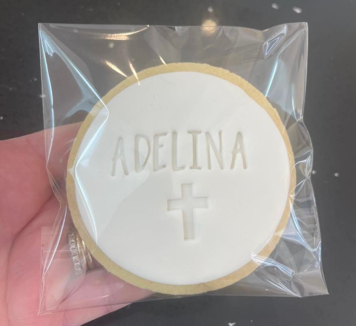A person is holding a cookie with the name adelina on it