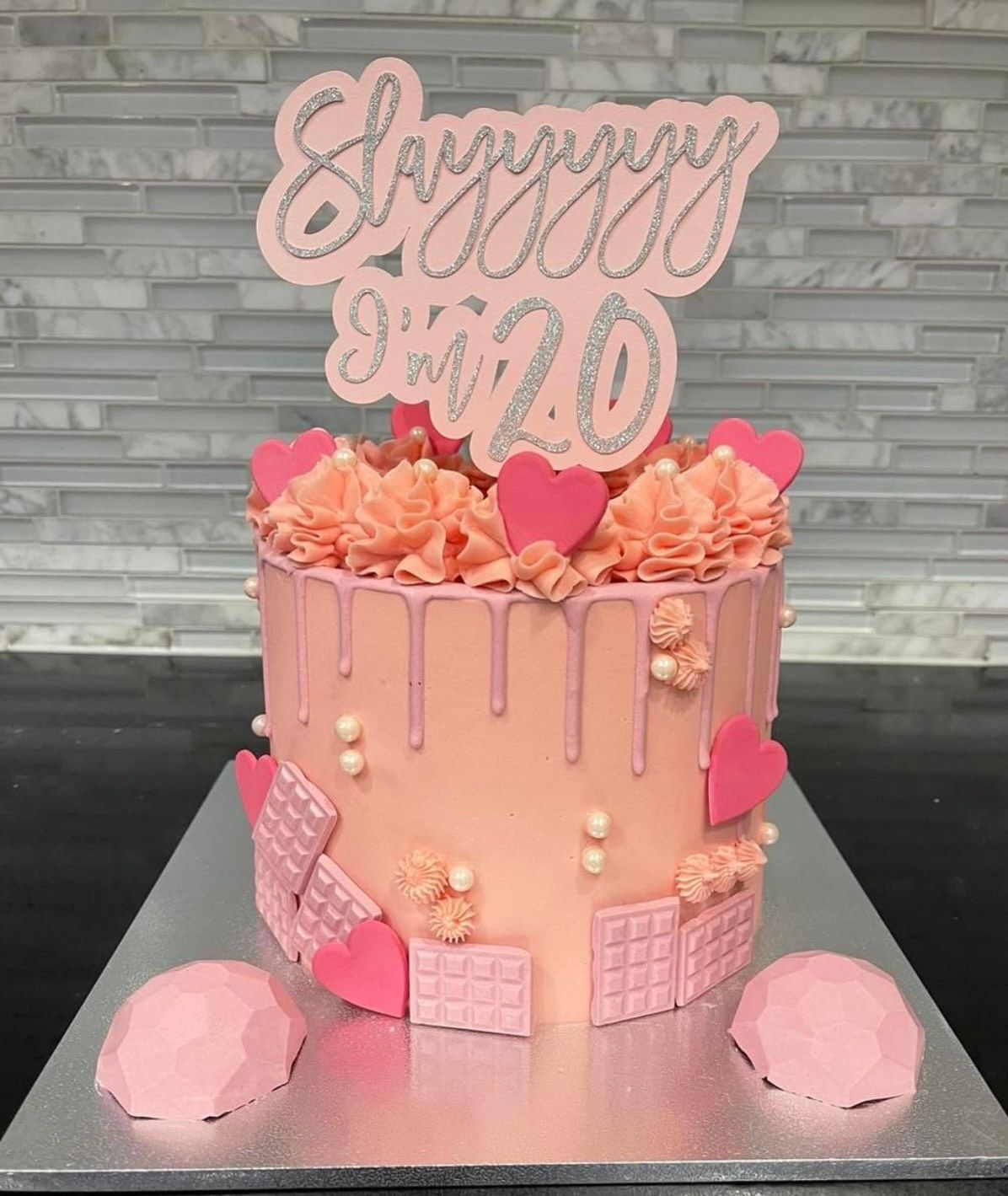 A pink cake with a topper that says happy sweet 20