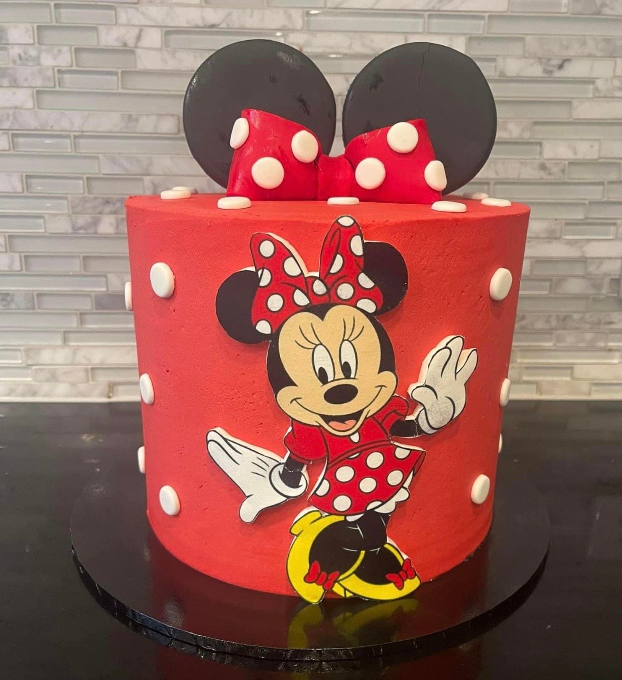 A red cake with minnie mouse on it is sitting on a table.