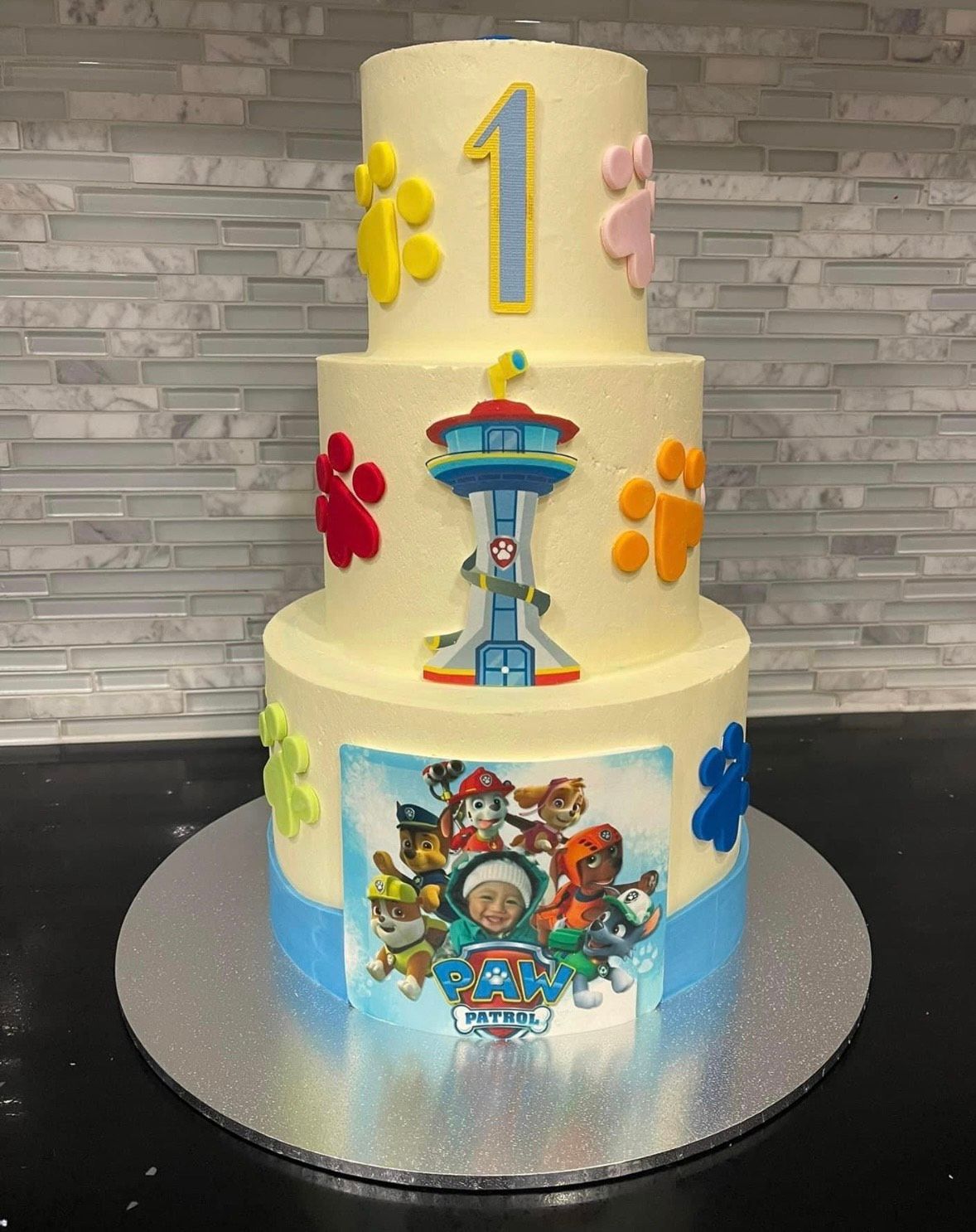 A three tiered cake with a picture of paw patrol on it.