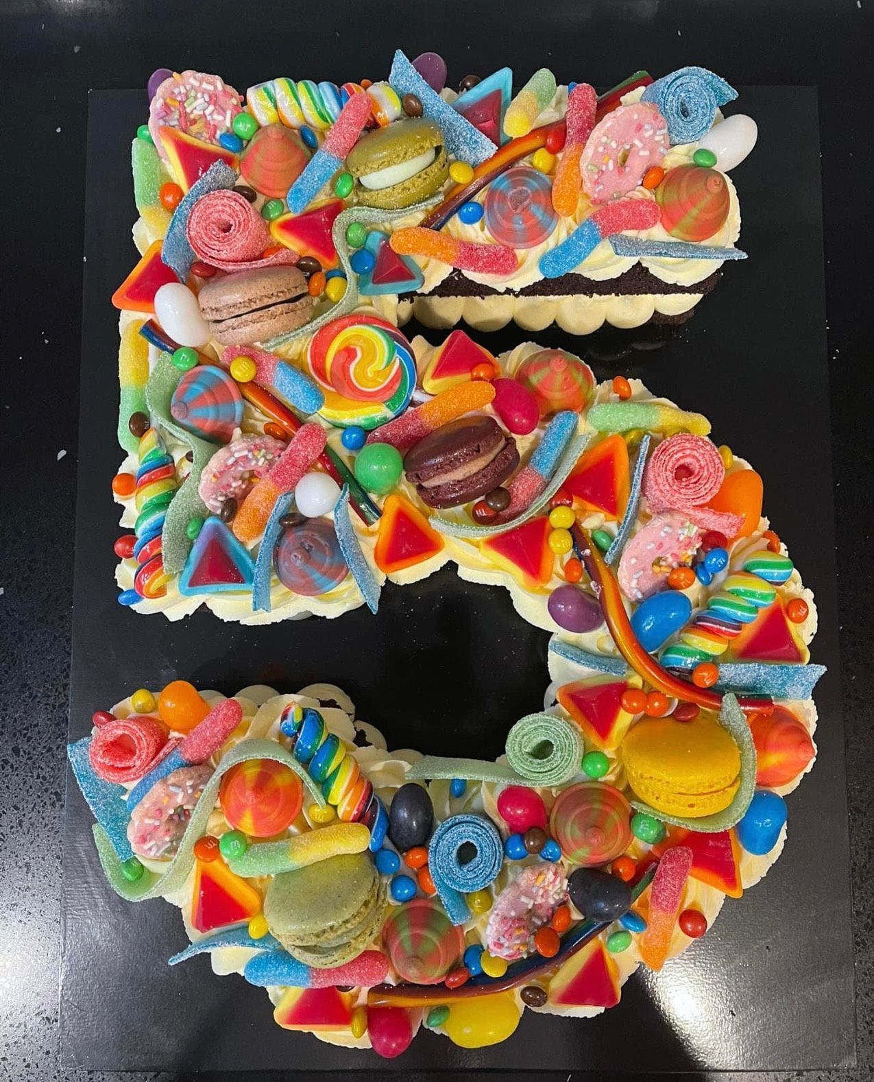 A cake in the shape of the number 5 covered in candy
