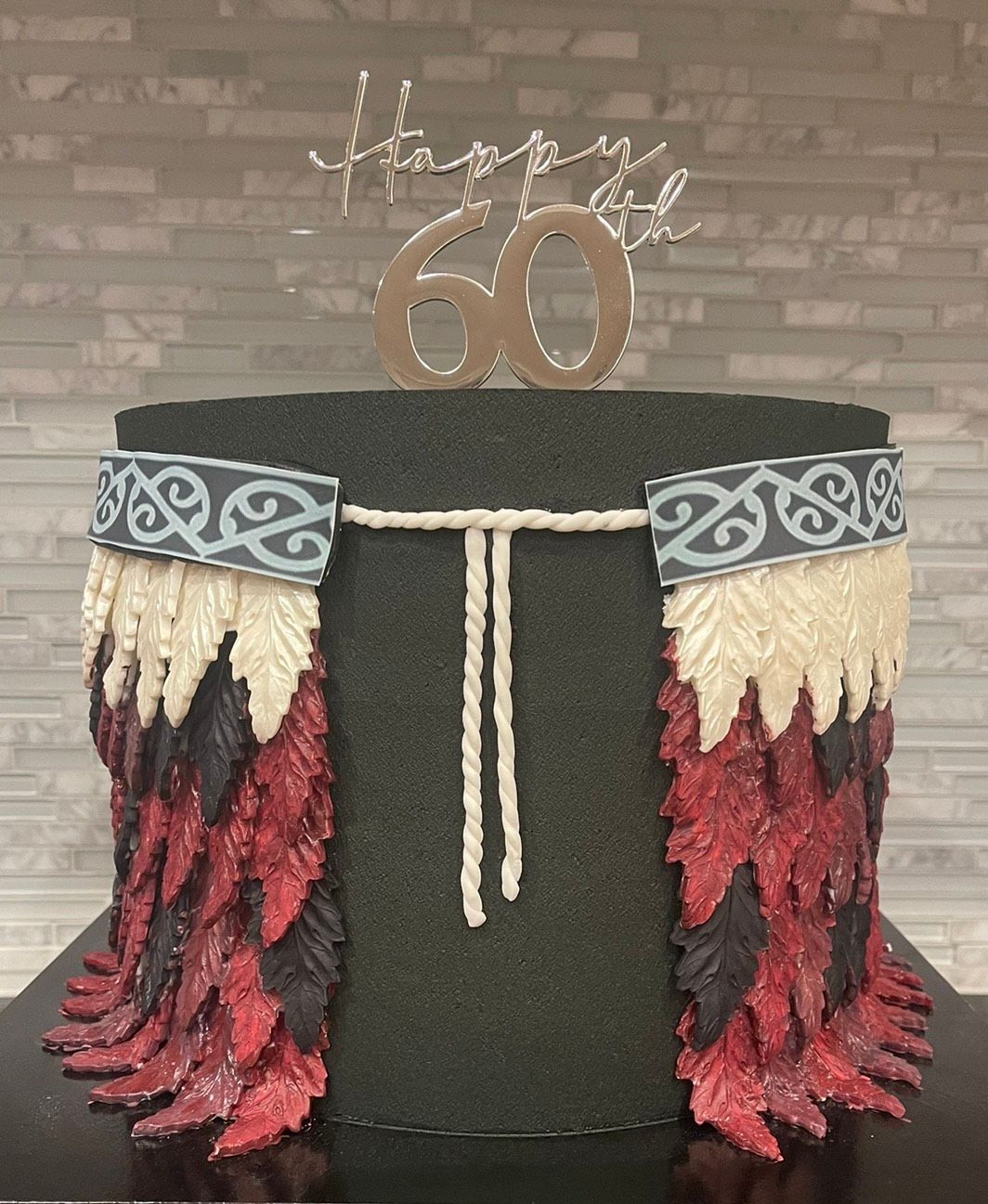 A cake with feathers and the number 60 on top of it.
