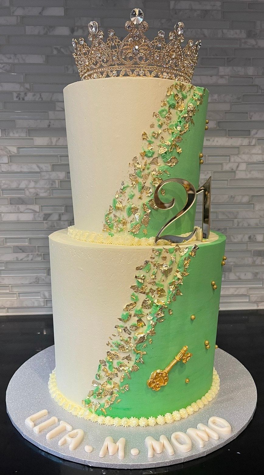 A white and green cake with a crown on top of it.