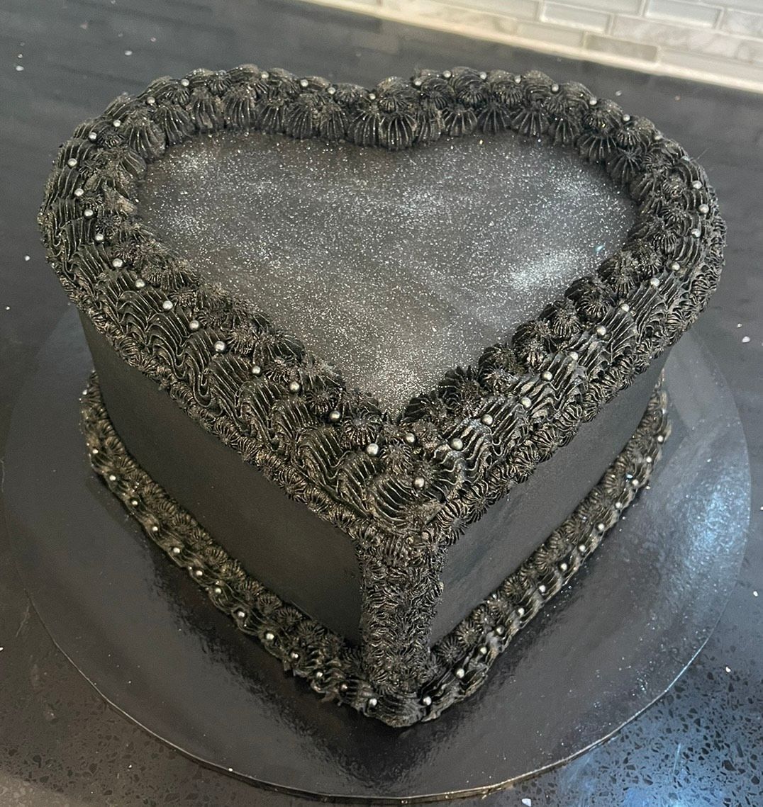 A black heart shaped cake on a black plate