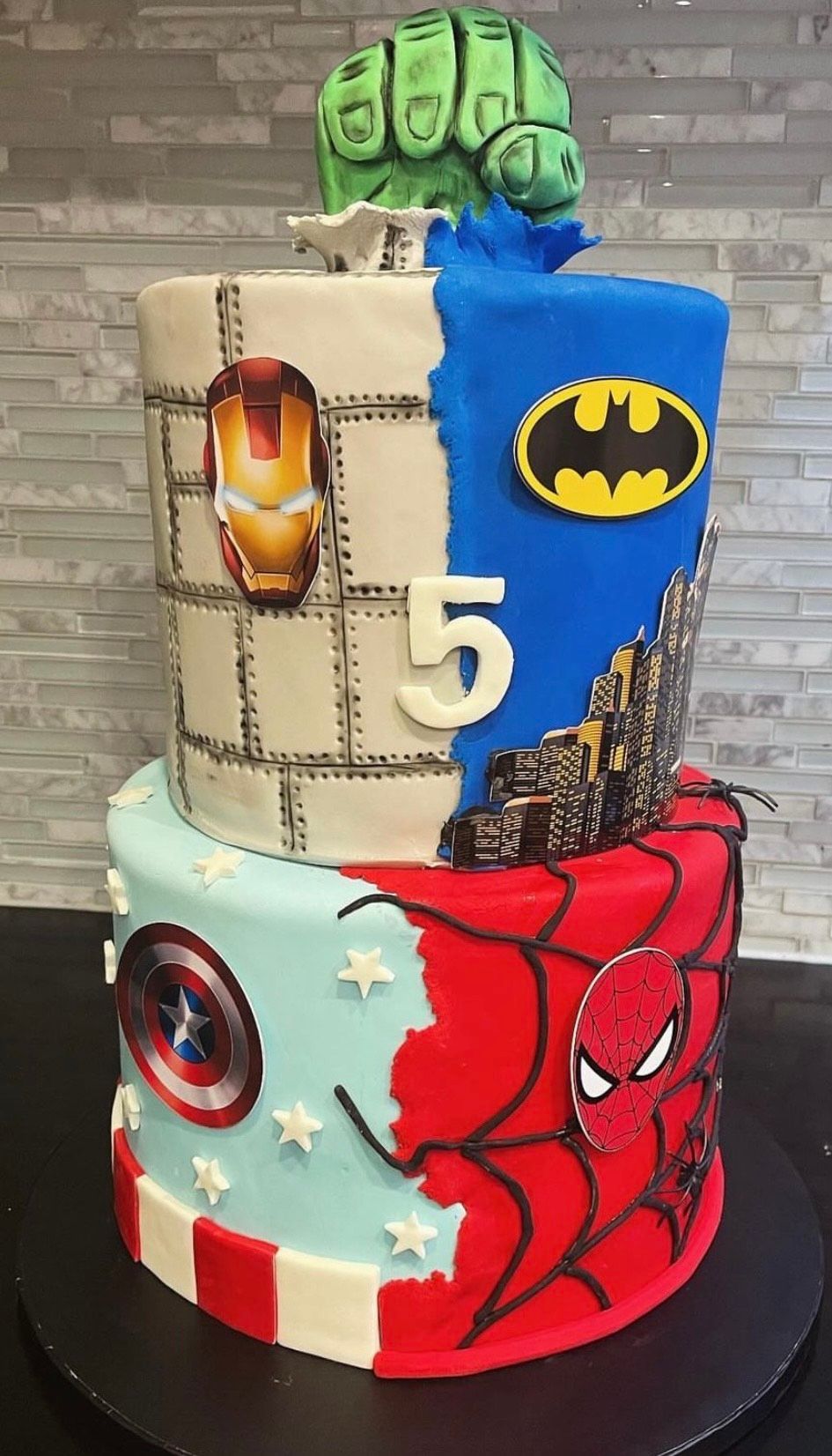 A cake with a hulk , batman , captain america , and iron man on it.