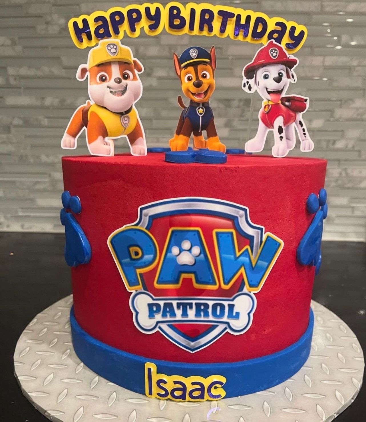 A red cake with paw patrol characters on top of it