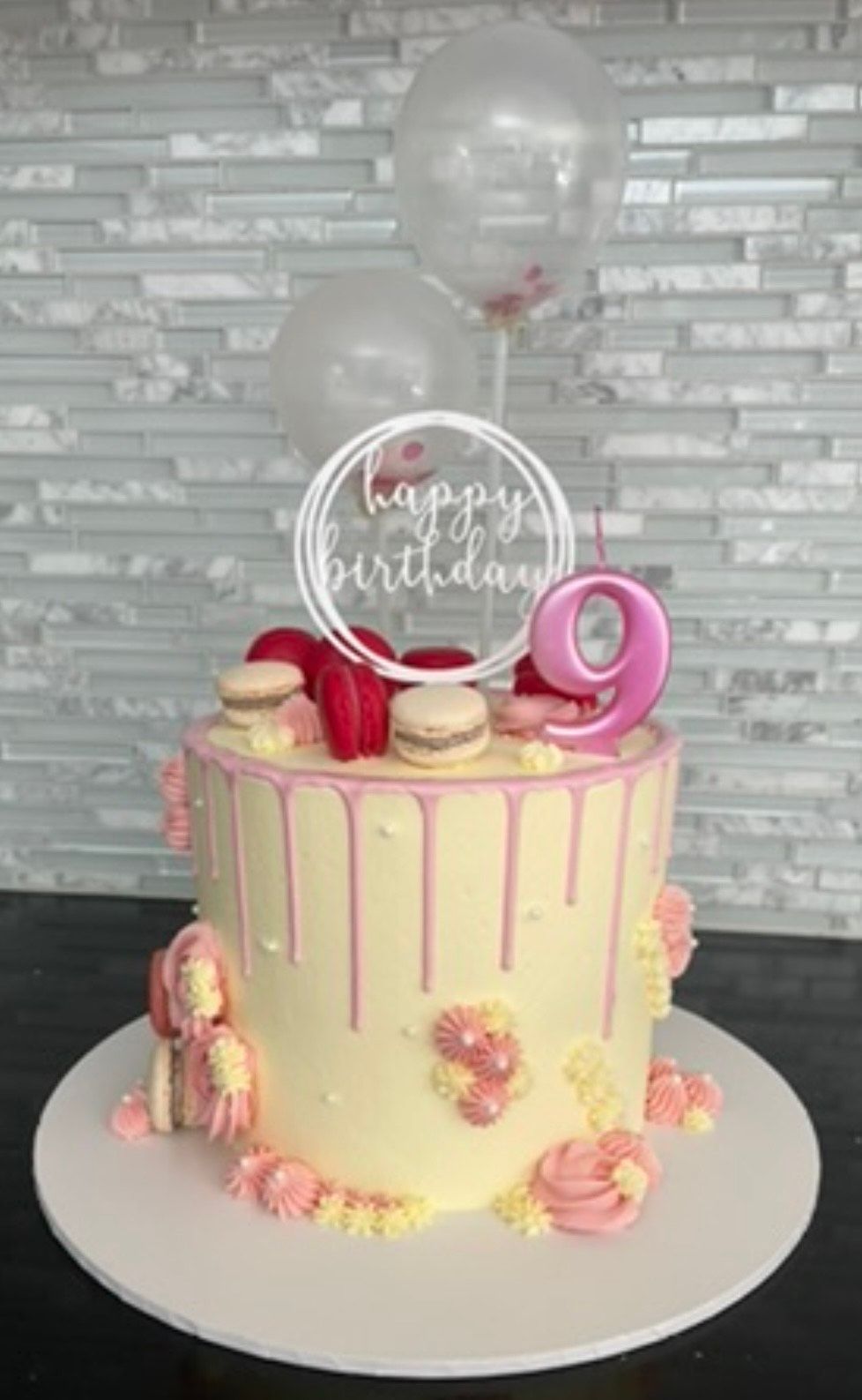 A birthday cake for a girl with balloons on top of it.