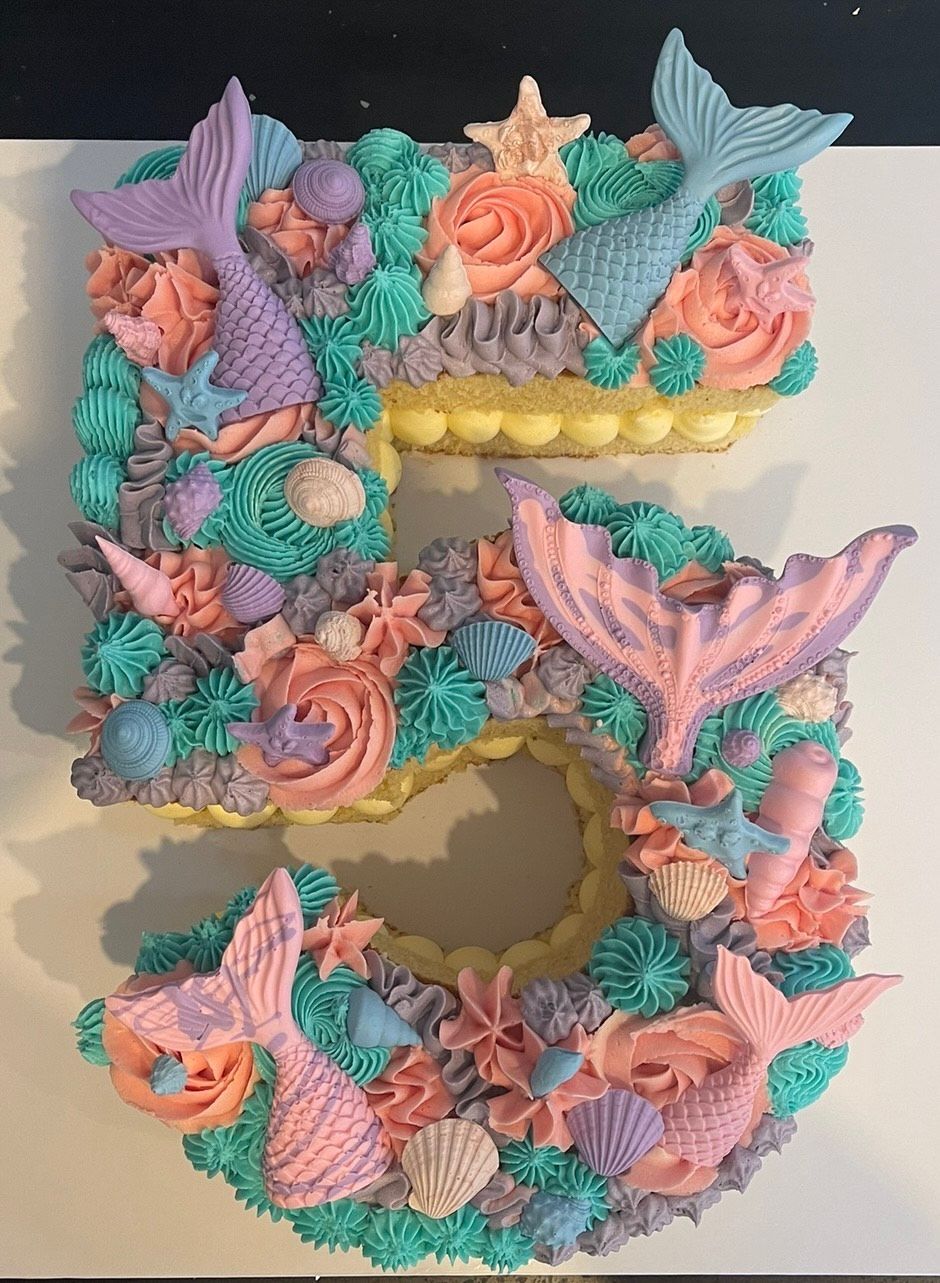 A number 5 cake decorated with mermaid tails and seashells